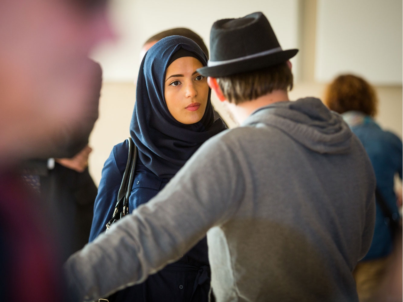 a girl with a headscarf talks to a boy with a hat