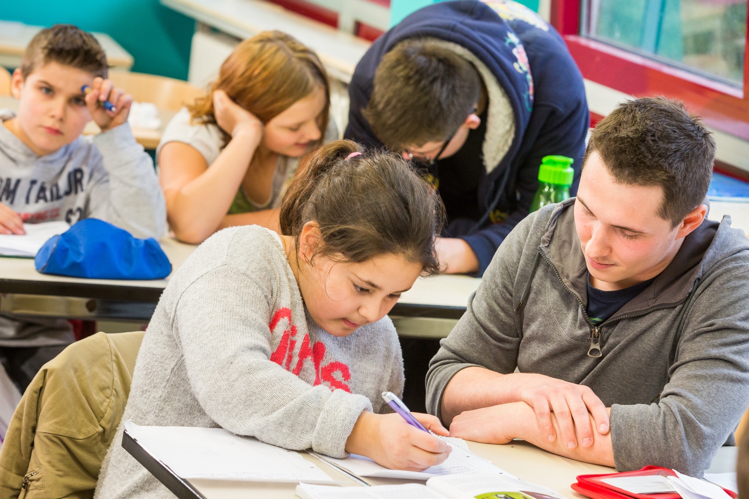 Eine Schülerin mit Kopftuch unterhält sich mit einem Schüler, der einen Hut trägt