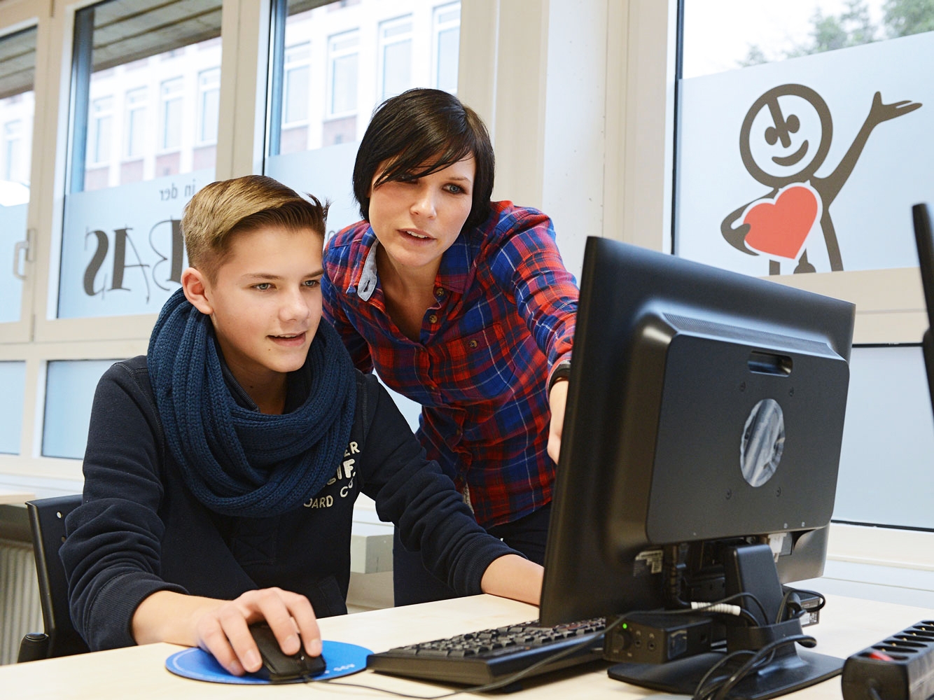 A student works with the help of his teacher at a computer from the Talent Company
