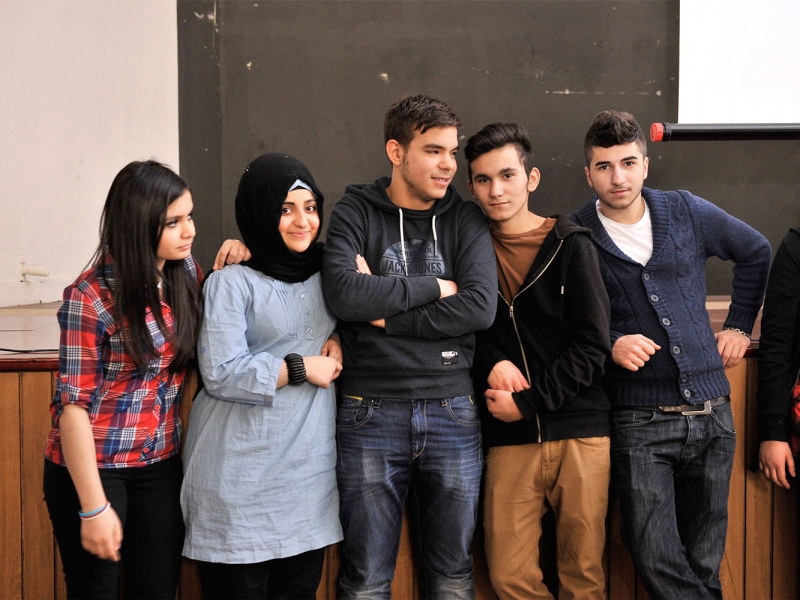 Five pupils of different origin in front of a blackboard