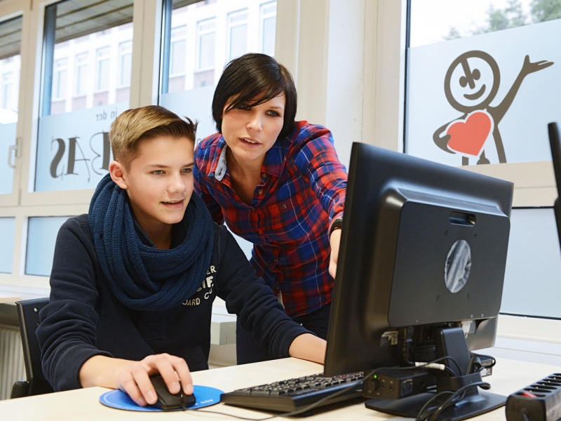 A student works with the help of his teacher at a computer from the Talent Company